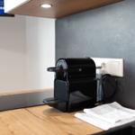 Küchenbereich mit Kaffeemaschine, Kochfeld und Handtuch auf Holzoberfläche.