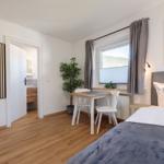 Schlafzimmer mit Bett, Tisch, Stühlen und Blick auf die Berge.