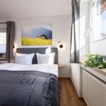 Schlafzimmer mit Bett, Wandbild und Fenstern mit Blick auf Berge.