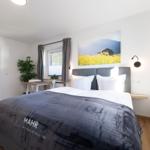 Schlafzimmer mit Doppelbett, Wandbild und Fenster. Blick in angrenzenden Raum.