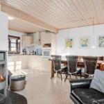 Kitchen, dining area, and living space with wood-burning stove and leather sofa.