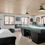 Room with pool table, sofa, windows, and ceiling lights.