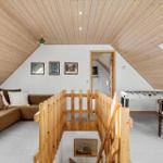 Attic room with sofa, foosball table, and wooden railing.