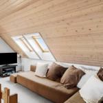 Living room with sofa, TV, and skylights under wooden ceiling.