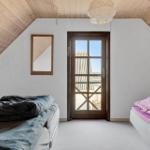 Two beds under wooden ceiling, glass door, mirror, and ceiling light.