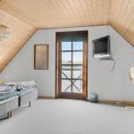 Bedroom with wooden ceiling, bed, TV, and door to balcony.