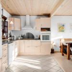 Kitchen with wooden ceiling, white appliances, and dining area with table and chairs.