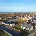 Village with houses and beach in the background.