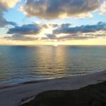 Sunset over sea and beach with clouds on the horizon.