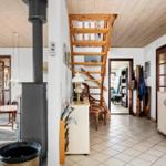 Kitchen with white appliances, wooden staircase, and wood stove inside.