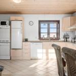 Kitchen with wooden ceiling, white appliances, and dining area with wicker chairs.