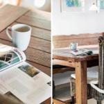 Wooden table with mug and newspaper. Rattan chair and wooden bench in background.