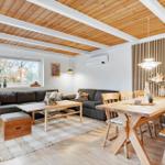 Wohn- und Essbereich mit Holzdecke, Sofa, Esstisch und Sitzbank.