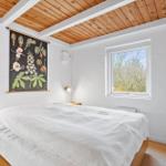 Schlafzimmer mit Bett, Holzdecke und Fenster. Wandbild und Nachttische.