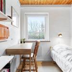 Ein Schlafzimmer mit Bett, Schreibtisch, Stuhl und Fenster. An der Wand hängen Bücherregale.
