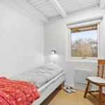 Ein Schlafzimmer mit einem Bett, einem Stuhl und einem Fenster. Eine Akustikgitarre hängt an der Wand.