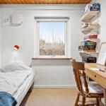 Ein Zimmer mit Bett, Schreibtisch und Fenster. An der Wand hängt eine Lampe.