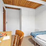 Ein Schlafzimmer mit einem Bett, einem Schreibtisch und einer Holztür.