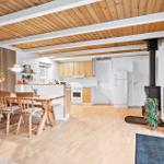 Wohnküche mit Holzboden, Essbereich und Kaminofen. Holzdecke und moderne Einrichtung.
