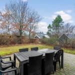 Terrasse mit Tisch und Stühlen, Garten und Bäume im Hintergrund.