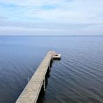 Holzsteg führt über ruhiges Wasser zu einer kleinen Plattform.