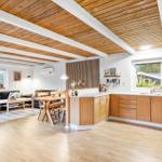Küche mit Holzschrank und Essbereich. Wohnzimmer mit Sofa und Fenster.