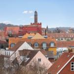 Panoramic view over Danish town with red roofs and prominent tower in the background.