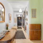 Hallway with wooden console, mirror, and wall decor. Wooden cabinet and rug visible.