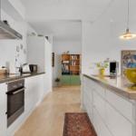 Kitchen with white built-in cabinetry, stainless steel countertop, and view to terrace.