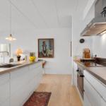 Kitchen with worktop, stove, and extractor. Wooden floor and wall pictures.