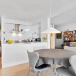 Dining area with round table and chairs. Kitchen and living room in background.