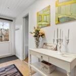 Entrance area with white walls, wooden floor, and a white table with vases and candles.
