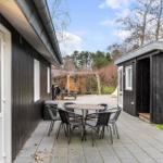 Terrace with table and chairs in front of a wooden house. Playground and forest in background.