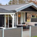 Terrace with sofa, table, and garden fence. Glass doors lead to the interior.