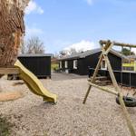 Backyard with playground, swing, and slide in front of a black house.