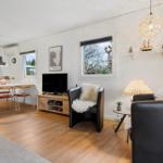 Living and dining area with TV, two armchairs, and kitchen area in background.