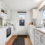 Kitchen with white cabinets, countertop, and window. Door leads outside.