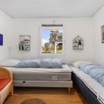Two beds and a chair in the bedroom with garden view through window.