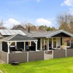 Modern holiday home with terrace, garden, and solar panels. Living area with seating.