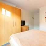 Schlafzimmer mit Bett, Kleiderschrank und Fernseher.