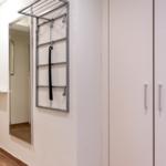 Flur mit Spiegel, Kleiderständer und Schrank. Tür und Bodenfliesen sichtbar.