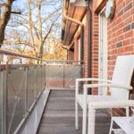 Terrasse mit weißem Stuhl, Tisch und Sektflasche an roter Ziegelwand.