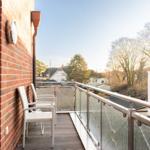 Terrasse mit zwei weißen Stühlen und Blick auf Wohnhäuser und Bäume.