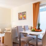 Essbereich mit Tisch, Stühlen und Obst. Wohnbereich mit Sofa und Kamin.