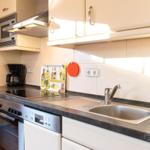 Küche mit Arbeitsplatte, Spüle, Kochfeld und integriertem Backofen.