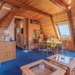 Wohnraum mit Holzdecke, Treppe und Esstisch unter Dachschrägen.