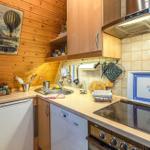 Küche mit Holzwand, Spüle, Herd und Geschirrspüler. An der Wand hängt ein Poster.