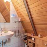 Bad mit Waschbecken, Spiegel und Holzwand unter Dachschräge.