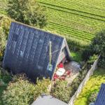 Haus mit Terrasse, umgeben von Weinreben und Grünflächen.
