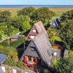 Häuser mit Dachterrassen stehen in grüner Umgebung neben Feldern und einem See.